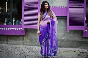 garota hindu indiana no tradicional saree violeta posou na rua contra janelas roxas. foto