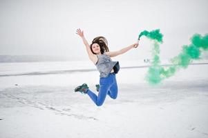jovem com bomba de fumaça de cor verde na mão em dia de inverno. foto