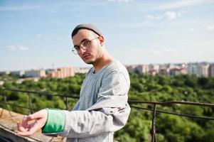 sonhador elegante macho de terno cinza, chapéu e óculos posou no telhado. foto