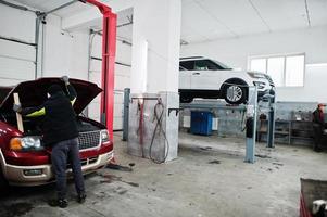 dois carros suv americanos em suporte para verificação de cambagem de alinhamento de rodas na oficina da estação de serviço. foto