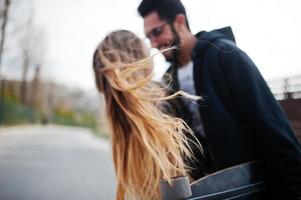 legal casal multirracial andando junto com longboard. cabelo no ar. foto