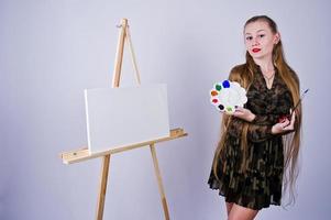 pintor de artista de mulher bonita com pincéis e tela a óleo posando em estúdio isolado no branco. foto