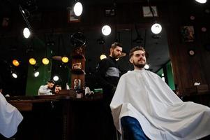 homem barbudo bonito na barbearia, barbeiro no trabalho. foto