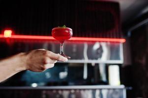 coquetel vermelho alcoólico com hortelã na mão do barman. foto