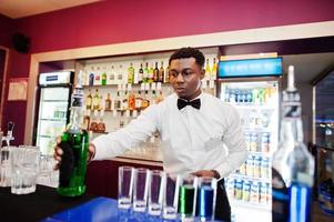 barman americano africano no bar fazendo coquetéis em tiros. preparação de bebidas alcoólicas. foto