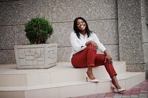 mulher de negócios afro-americana formalmente vestida de blusa branca e calça vermelha. empresária bem sucedida de pele escura. foto