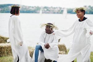 três amigos afro-americanos em capas brancas e grinalda se divertindo juntos. foto