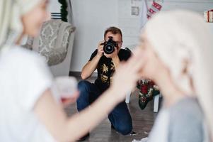 fotógrafo de homem atirando no estúdio duas garotas enquanto elas fazem seu próprio creme de máscaras. fotógrafo profissional no trabalho. foto