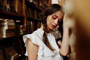 menina com tranças na blusa branca na antiga biblioteca. foto