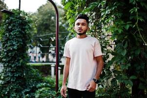 homem de barba indiana elegante na camiseta rosa. modelo da índia posou ao ar livre nas ruas da cidade. foto