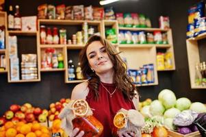 garota de vermelho segurando geléia em uma jarra na loja de frutas. foto