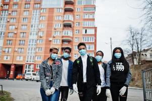 grupo de amigos adolescentes africanos contra a rua vazia com construção usando máscaras médicas protegem contra infecções e doenças quarentena de vírus coronavírus. foto