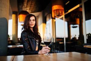 jovem mulher encaracolada desfrutando de seu vinho em um bar. foto
