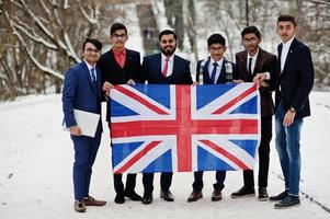 grupo de seis empresário indiano de terno posou ao ar livre em dia de inverno na europa com bandeira da grã-bretanha. relações amistosas com a Índia e o Reino Unido. foto