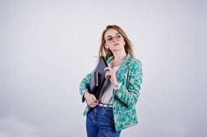 menina loira elegante de jaqueta e jeans em óculos com diário de notebook e laptop nas mãos contra um fundo branco no estúdio. foto