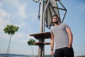 modelo de homem de barba árabe alto bonito na camisa despojada posou ao ar livre contra o painel solar. cara árabe na moda. foto