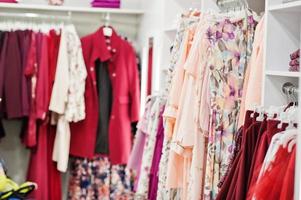 conjunto de roupas coloridas rosa femininas nas prateleiras e prateleiras na loja de roupas nova boutique moderna. coleções de vestidos de primavera verão. foto