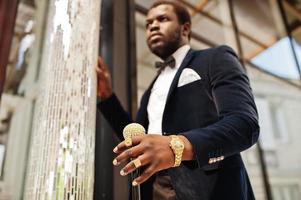 homem afro-americano elegante bonito com roupa formal e gravata borboleta com bengala. foto