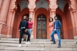 quatro amigos africanos posaram ao ar livre contra a arquitetura antiga. duas meninas negras com caras. foto