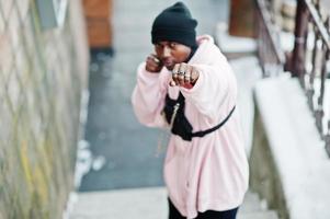 homem afro-americano de estilo urbano elegante com capuz rosa posou no dia de inverno e mãos de boxe. foto