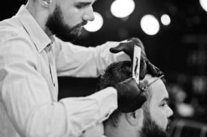 homem barbudo bonito na barbearia, barbeiro no trabalho. foto