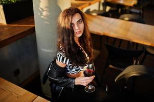 jovem mulher encaracolada desfrutando de seu vinho em um bar. foto