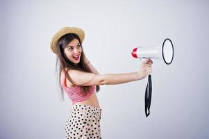 retrato de uma linda jovem em traje de banho e chapéu fala em megafone no estúdio. foto