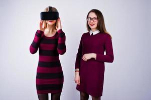 duas garotas de vestidos roxos experimentando óculos de realidade virtual no estúdio. foto