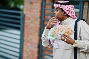 homem de negócios árabes do Oriente Médio posou na rua contra um edifício moderno com bolsa preta e dinheiro do euro. foto