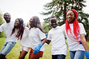 grupo de voluntários africanos felizes abraça juntos no parque. áfrica voluntariado, caridade, pessoas e conceito de ecologia. foto