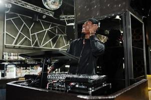 DJ afro-americano toca música em decks na boate. foto