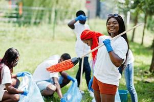 grupo de voluntários africanos felizes com área de limpeza de sacos de lixo no parque. áfrica voluntariado, caridade, pessoas e conceito de ecologia. foto