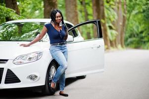 mulher afro-americana posou contra carro branco na estrada florestal. foto