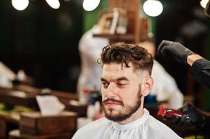 homem barbudo bonito na barbearia, barbeiro no trabalho. foto