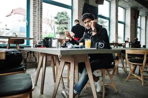 casual e elegante jovem asiático com fones de ouvido no café comendo sushi. foto