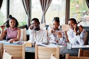 amigos africanos felizes sentados e conversando no café. grupo de negros reunidos em restaurante e se divertindo juntos. foto
