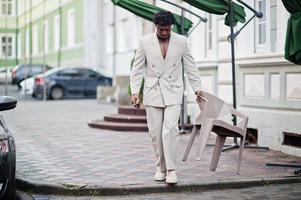 homem afro elegante em terno bege da velha escola com telefone celular. elegante jovem homem africano na jaqueta casual no torso nu. foto