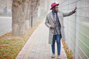 modelo de homem afro-americano elegante com casaco cinza, gravata e chapéu vermelho. foto