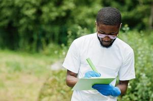 homem voluntário africano com prancheta no parque. áfrica voluntariado, caridade, pessoas e conceito de ecologia. foto