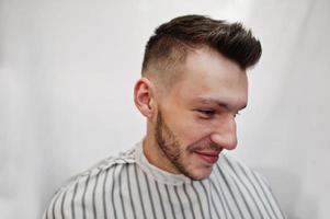 feche a cabeça do jovem barbudo cortando o cabelo na barbearia. alma de barbeiro. foto