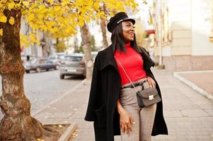 garota de moda afro-americana de casaco e boné de jornaleiro posou na rua. foto