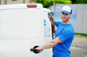 entregador na frente van de carga entregando garrafas de água. foto