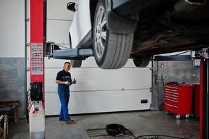 tema de reparação e manutenção de automóveis. mecânico de uniforme trabalhando em auto serviço. foto