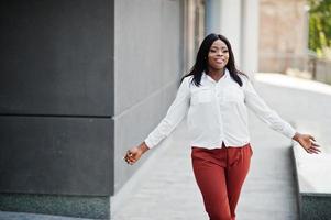 mulher de negócios afro-americana formalmente vestida de blusa branca e calça vermelha. empresária bem sucedida de pele escura. foto