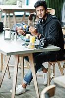 casual e elegante jovem asiático com fones de ouvido no café comendo sushi. foto