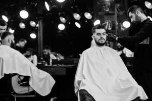 homem barbudo bonito na barbearia, barbeiro no trabalho. foto