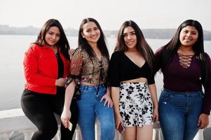 grupo de quatro meninas latinas felizes e bonitas do Equador posou contra o lado do lago. foto