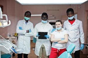 equipe multirracial de médicos dentistas. três médicos afro-americanos com uma médica caucasiana. foto