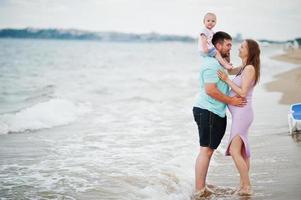 férias de verão. pais e pessoas atividade ao ar livre com crianças. boas férias em família. pai, mãe grávida, filha bebê na praia de areia do mar. foto