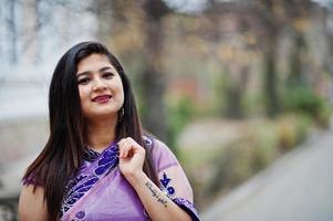 Feche o retrato da menina hindu indiana no tradicional saree violeta posado na rua. foto